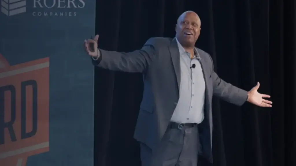 Walter Bond on stage with arms outstretched, speaking at the Roers Companies conference