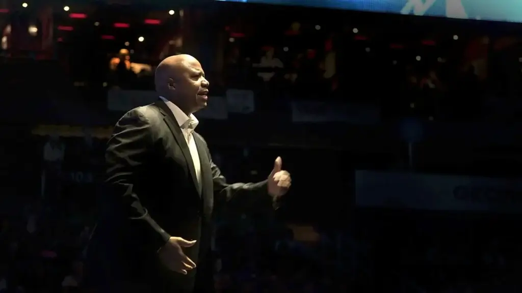 Walter Bond gesturing with a thumbs-up while speaking on stage at a corporate event